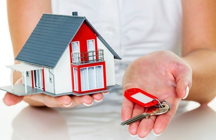 woman holding miniature house and house keys