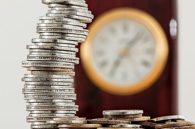 Understanding amortization could save you money this image shows a stack of coins in the foreground and a clock blurred in the background