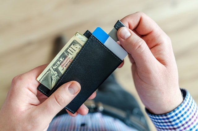 Man checking the contents of his wallet. Credit counseling can help you budget your spending money so you can pay off debt faster.