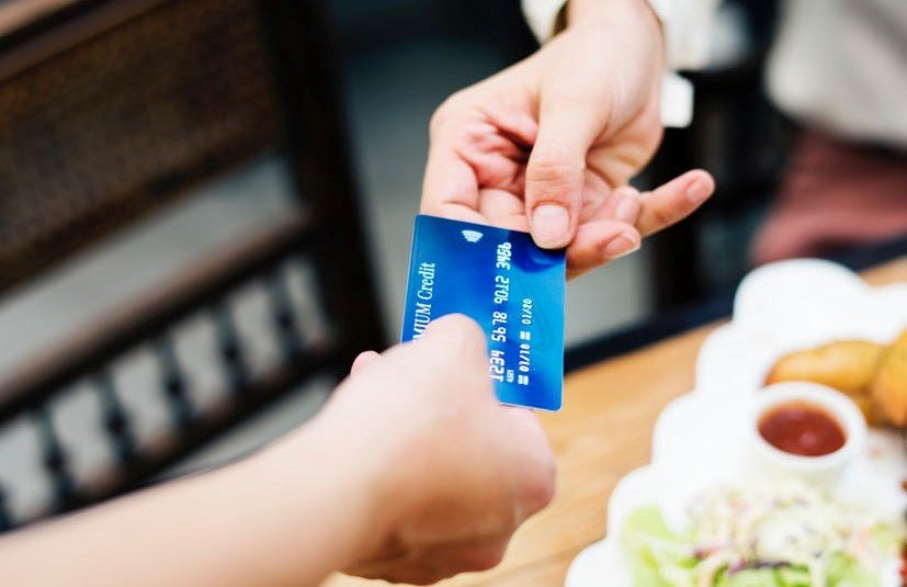 a person handing a credit card to another person