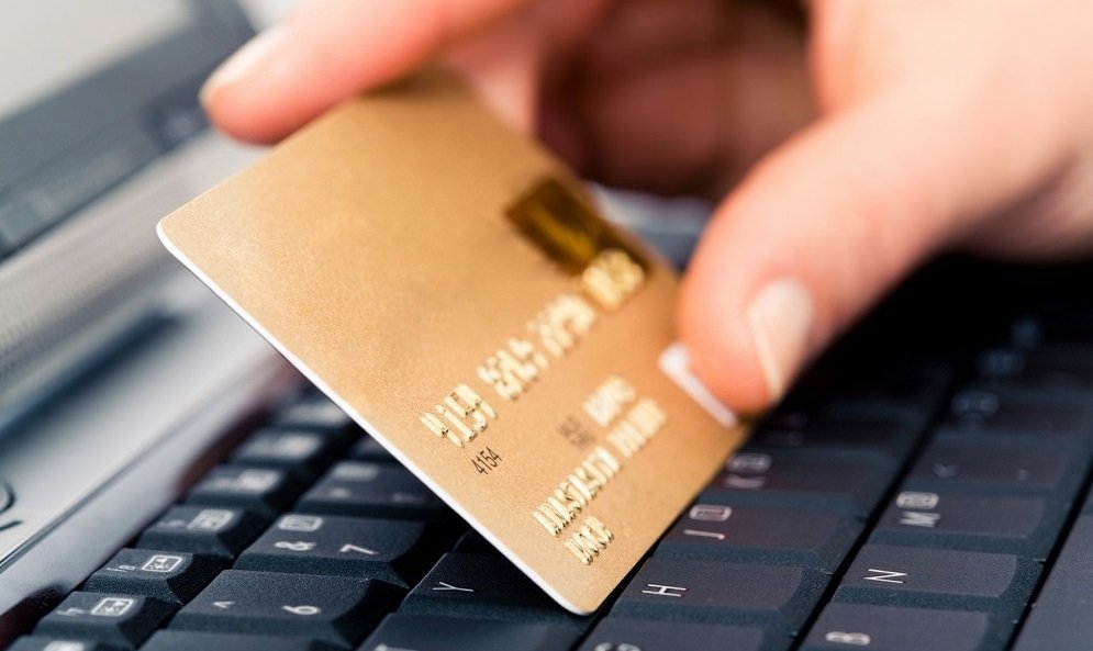 a person holding a credit card in front of the computer