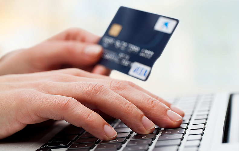 a person holding a credit card and touching the keyboard