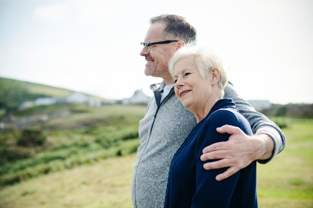 Smiling man holding woman's left shoulder
