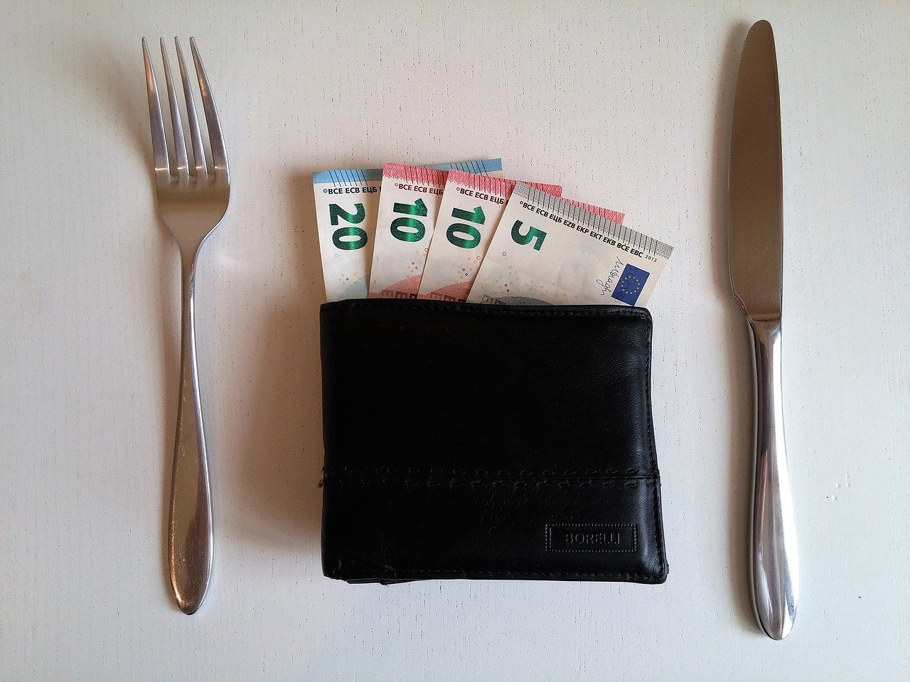 money in a wallet and fork and knife placed on right ang left sides