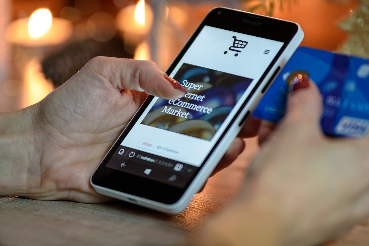 woman holding a smartphone on her left hand and credit card on right hand